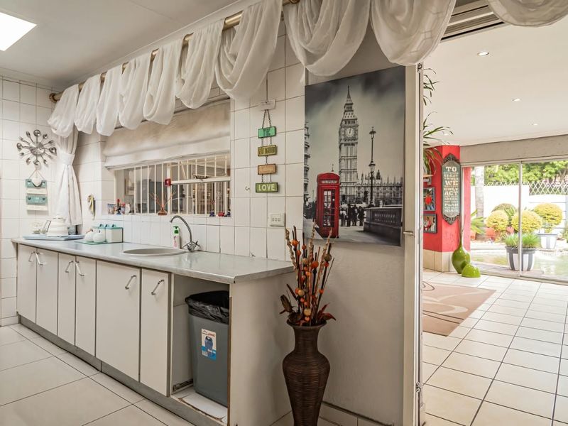 A functional scullery area featuring tiled flooring, built-in cabinetry, and a stainless steel sink, with direct access to the adjacent living space and patio.