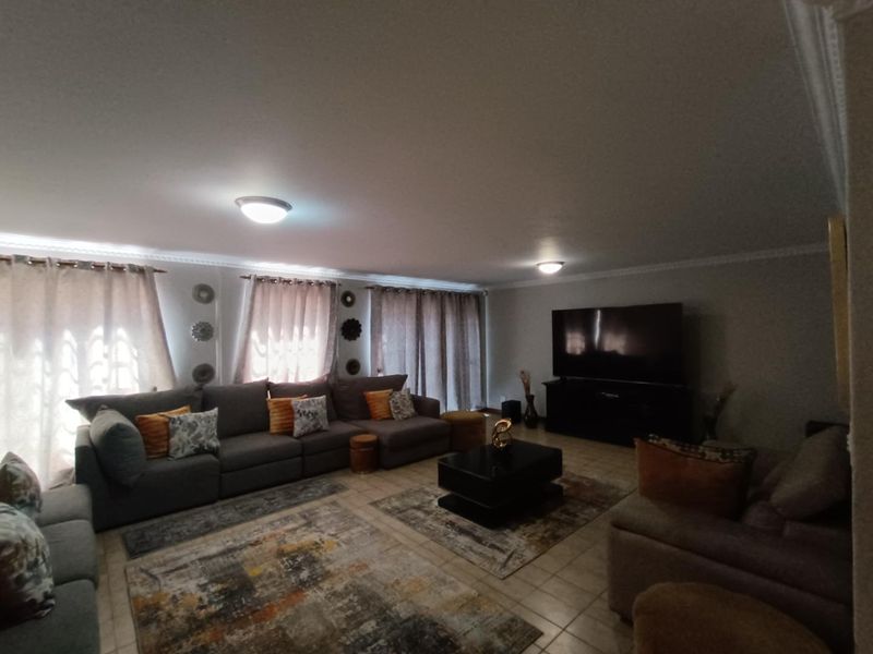 Spacious living room featuring tiled flooring, crown molding, and neutral wall finishes, providing a comfortable and functional area for relaxation.
