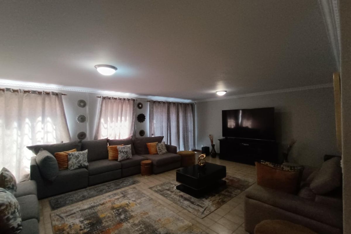 Spacious living room featuring tiled flooring, crown molding, and neutral wall finishes, providing a comfortable and functional area for relaxation.