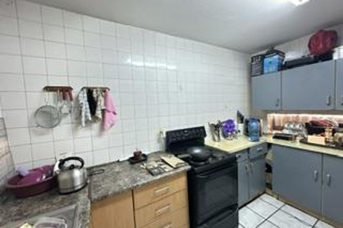 A functional kitchen featuring tiled walls, laminate countertops, and built-in cabinetry, offering a practical layout with a freestanding stove.
