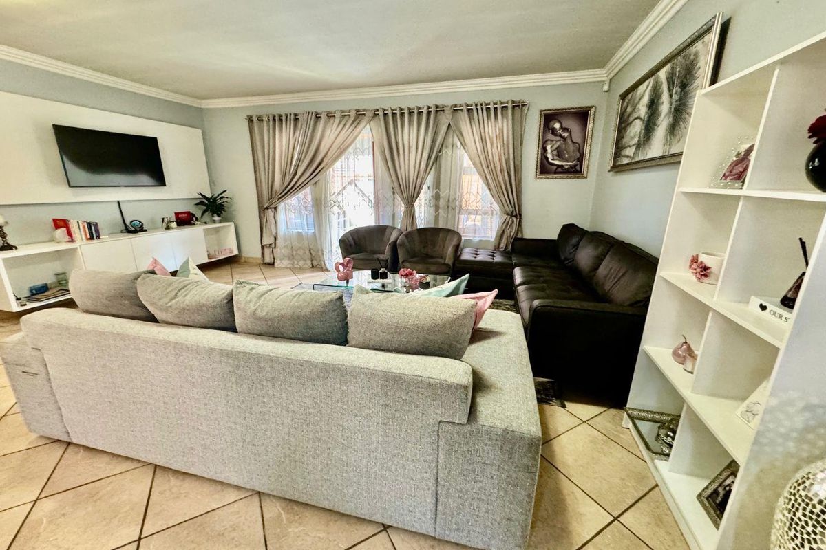 Spacious living room featuring tiled flooring, crown molding, and large sliding glass doors providing access to the outdoor area.