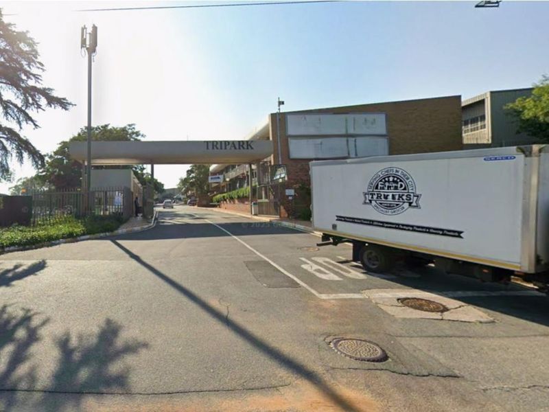 Front entrance view of the TriPark industrial complex featuring a security gate and paved access road.