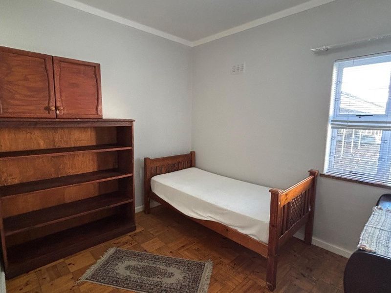 A bedroom featuring classic parquet flooring, a central ceiling light, and a window fitted with blinds.