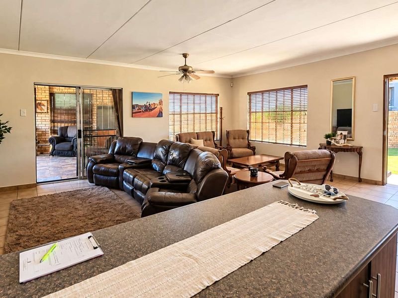 Spacious open-plan living area featuring tiled flooring, a ceiling fan, and direct access to the outdoor patio and garden.