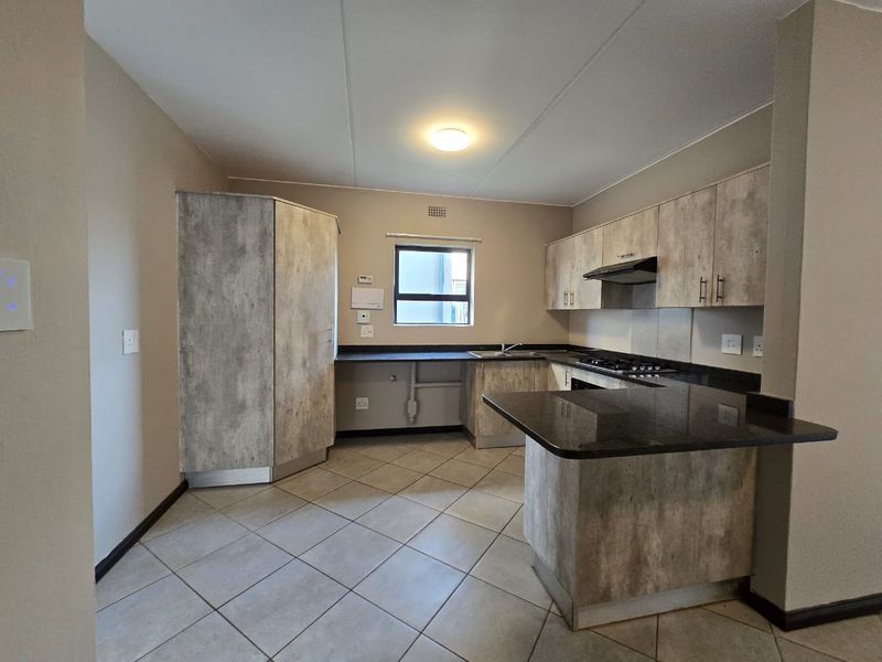Modern kitchen featuring textured cabinetry, granite countertops, a gas hob with extractor fan, and tiled flooring in an open-plan layout.