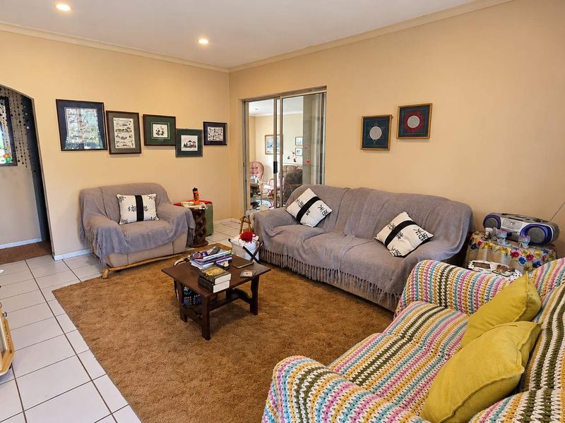 A spacious living room featuring tiled flooring, recessed lighting, and a sliding glass door providing access to an adjacent room.