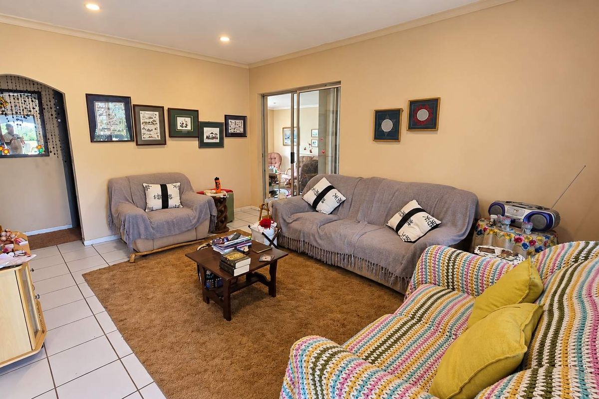 A spacious living room featuring tiled flooring, recessed lighting, and a sliding glass door providing access to an adjacent room.