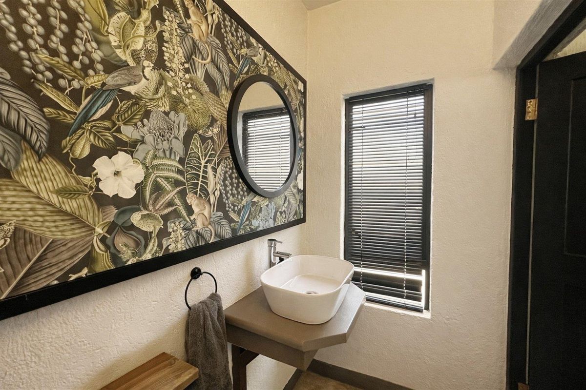 A modern guest bathroom featuring a vessel sink, wall-mounted vanity, and decorative botanical wallpaper.