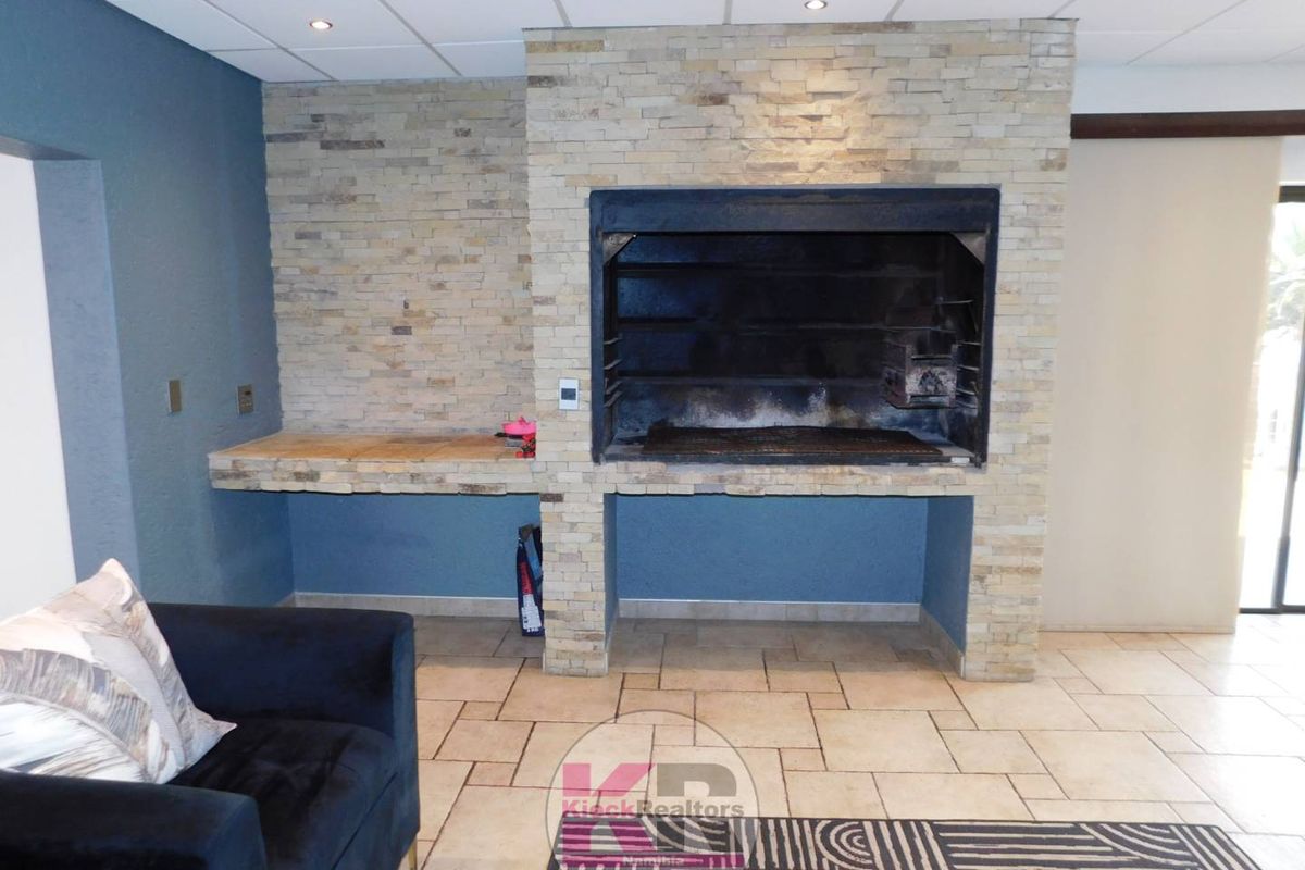 Living area featuring a prominent built-in braai with stone cladding and tiled flooring.
