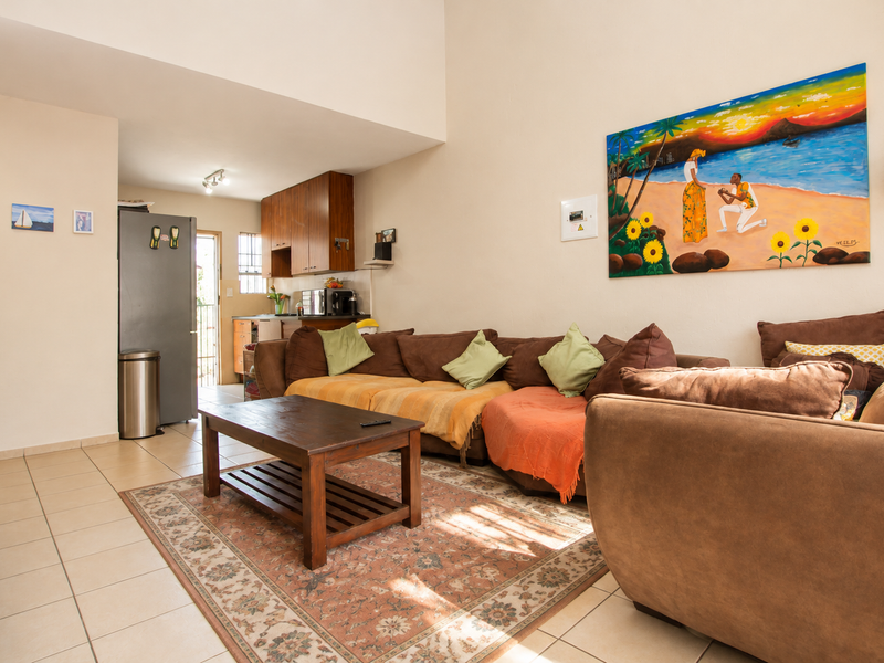 Open-plan living area featuring tiled floors, high ceilings, and an adjoining kitchen space with built-in cabinetry.