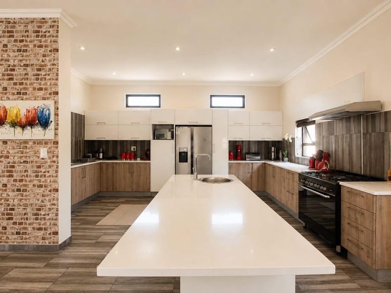 Modern kitchen featuring a large central island with quartz countertops, built-in oven, gas cooktop, and a stylish exposed brick feature wall.