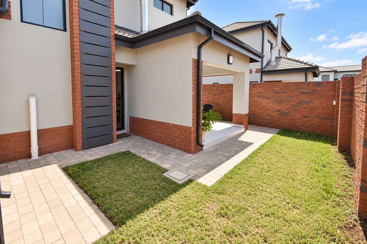 A well-maintained rear garden featuring a paved patio area, neat lawn, and brick boundary walls, providing a private outdoor space.