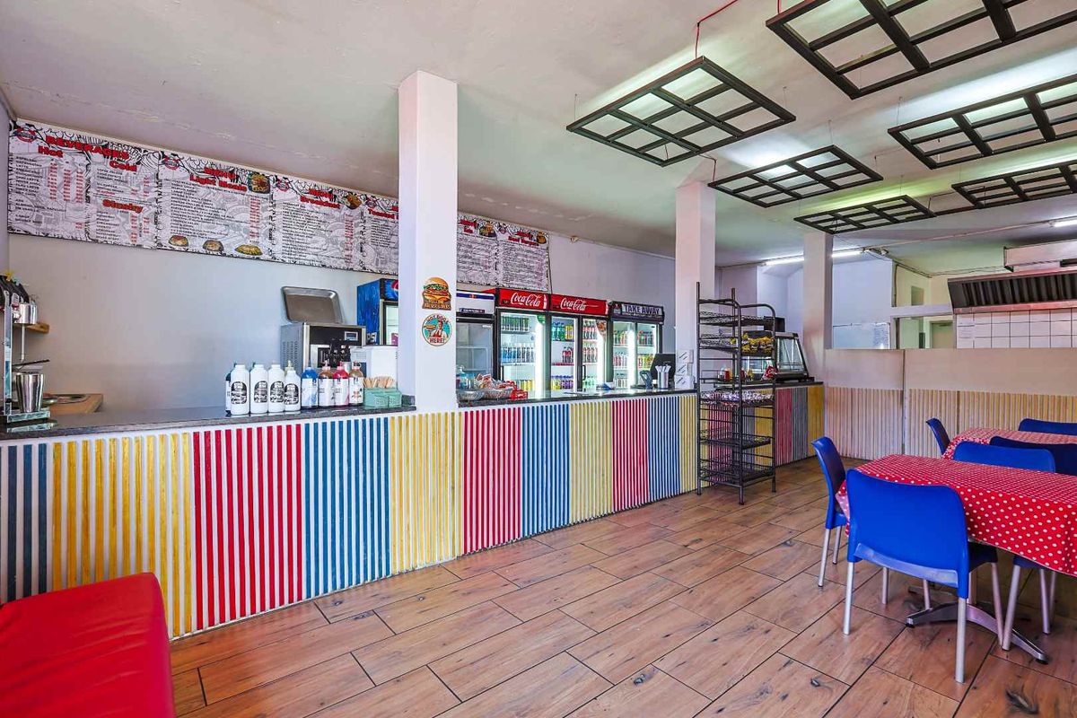 Open-plan commercial dining area featuring a service counter, tiled flooring, and suspended ceiling panels, suitable for a cafe or takeaway business.