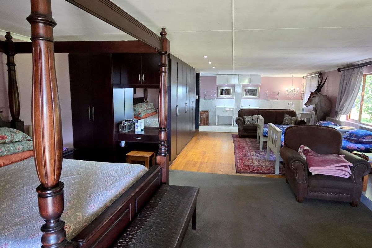 Spacious open-plan bedroom suite featuring built-in dark wood cabinetry, integrated vanity, and an en-suite bathroom area with dual basins.