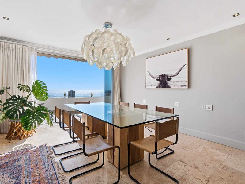 Bright dining room featuring elegant travertine flooring, recessed lighting, and seamless access to a balcony with expansive ocean views.
