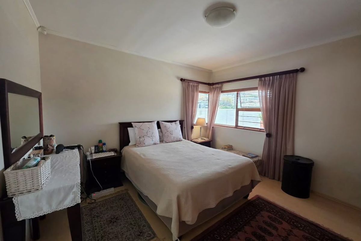 A functional bedroom featuring neutral walls, a ceiling light fixture, and a window with curtain rods.