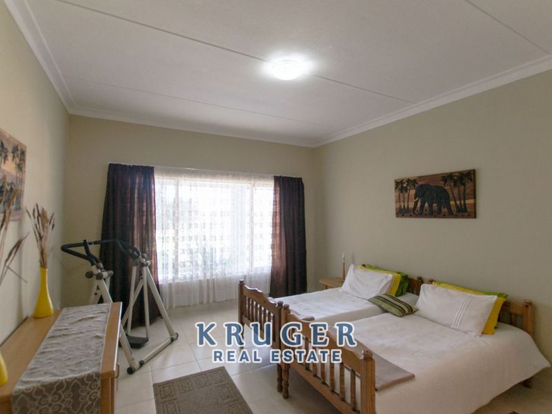 A spacious bedroom featuring tiled flooring, large windows with curtain rails, and a neutral color palette, offering a comfortable living space.