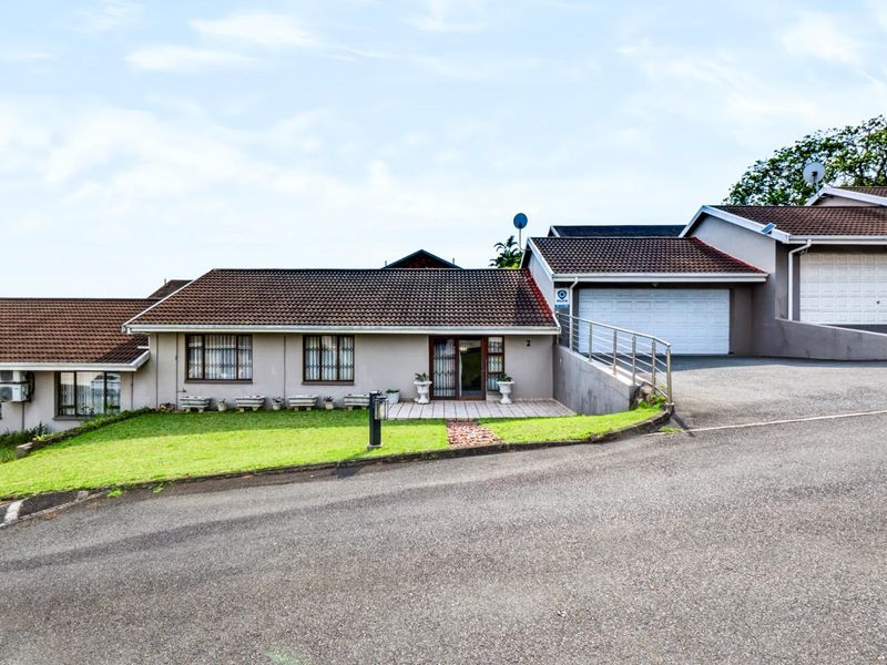 Front elevation of a townhouse featuring a tiled roof, paved entrance, and a double garage with a concrete driveway.