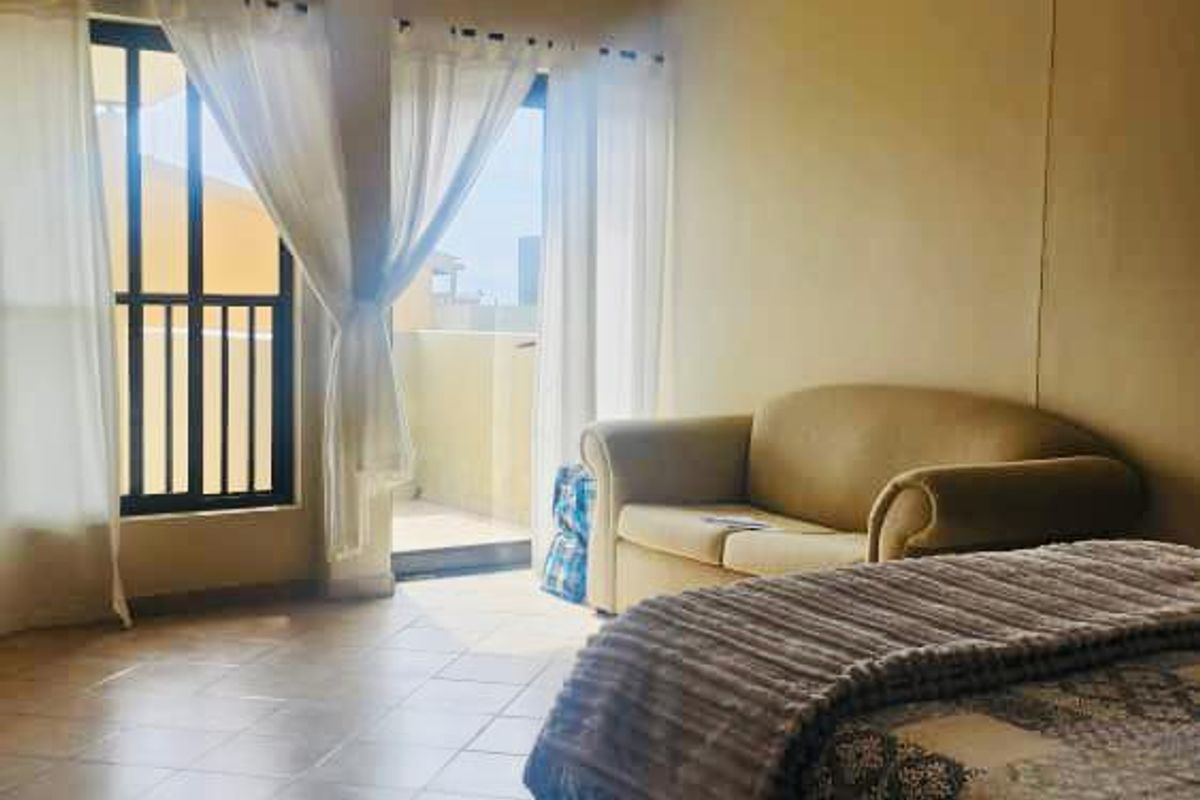 A spacious bedroom featuring tiled flooring and direct access to a private balcony through large glass sliding doors.