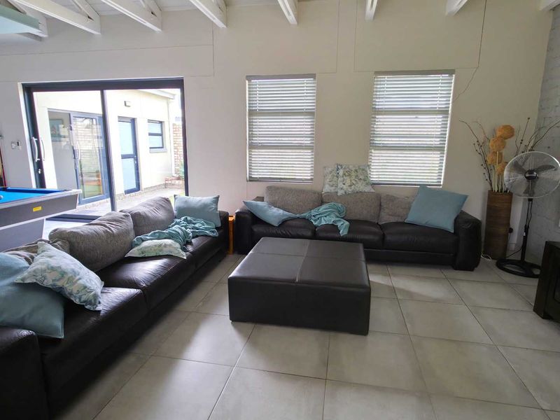 Spacious living area featuring exposed timber ceiling beams, large tiled flooring, and sliding glass doors providing access to the outdoor area.