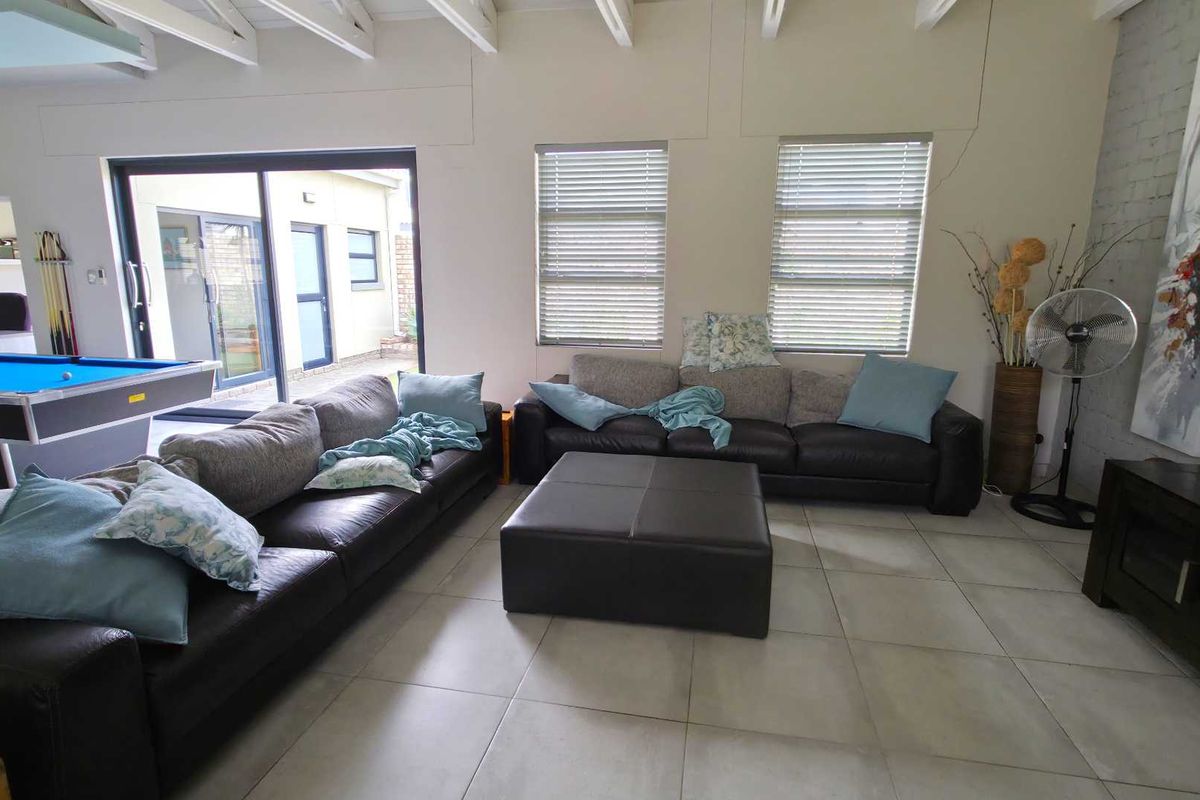 Spacious living area featuring exposed timber ceiling beams, large tiled flooring, and sliding glass doors providing access to the outdoor area.