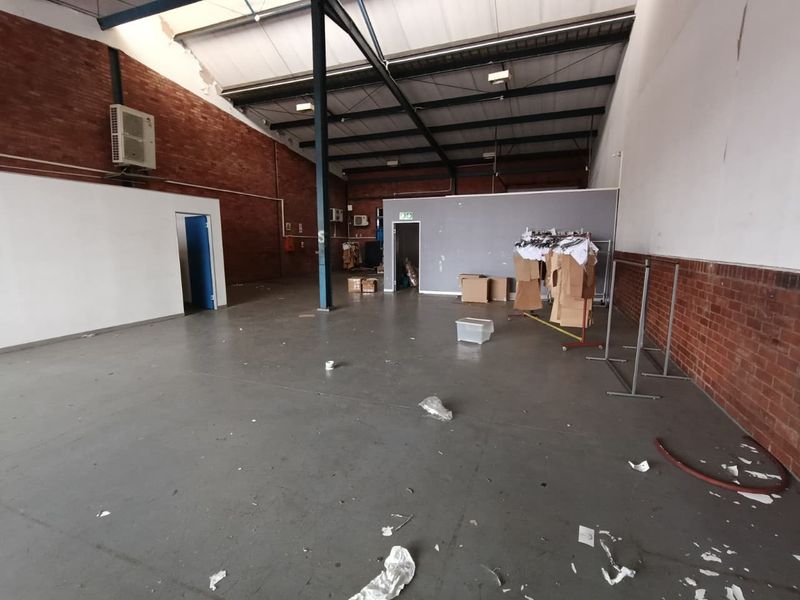 Spacious industrial utility area featuring exposed brick walls, steel roof trusses, and durable concrete flooring, suitable for warehouse or workshop use.