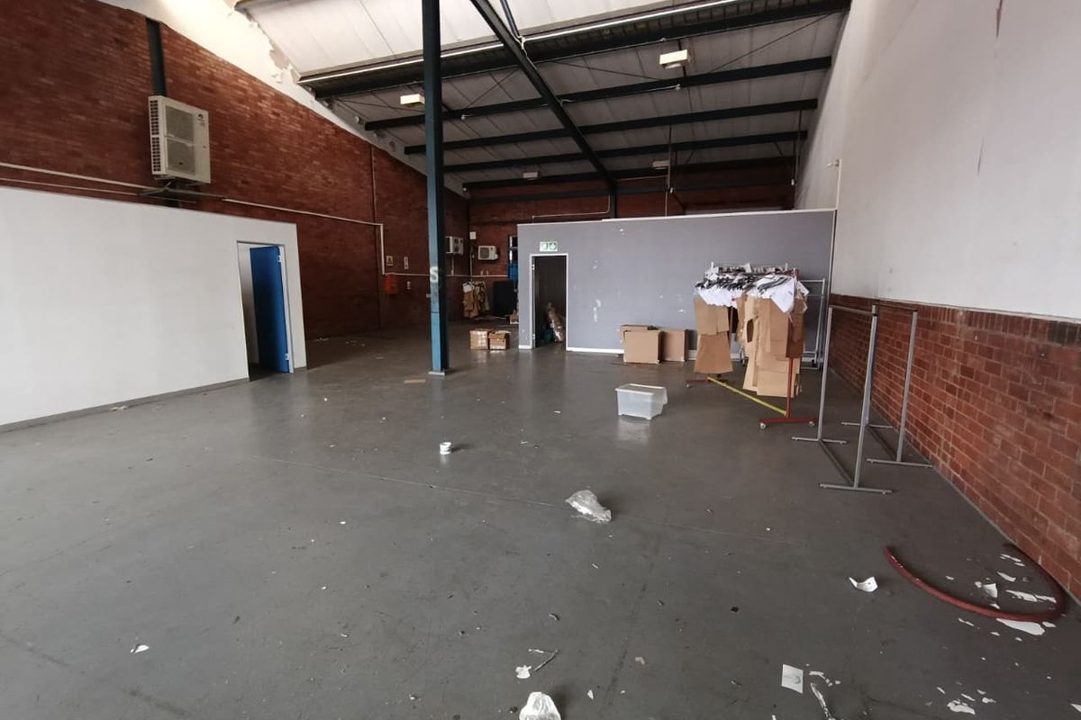 Spacious industrial utility area featuring exposed brick walls, steel roof trusses, and durable concrete flooring, suitable for warehouse or workshop use.
