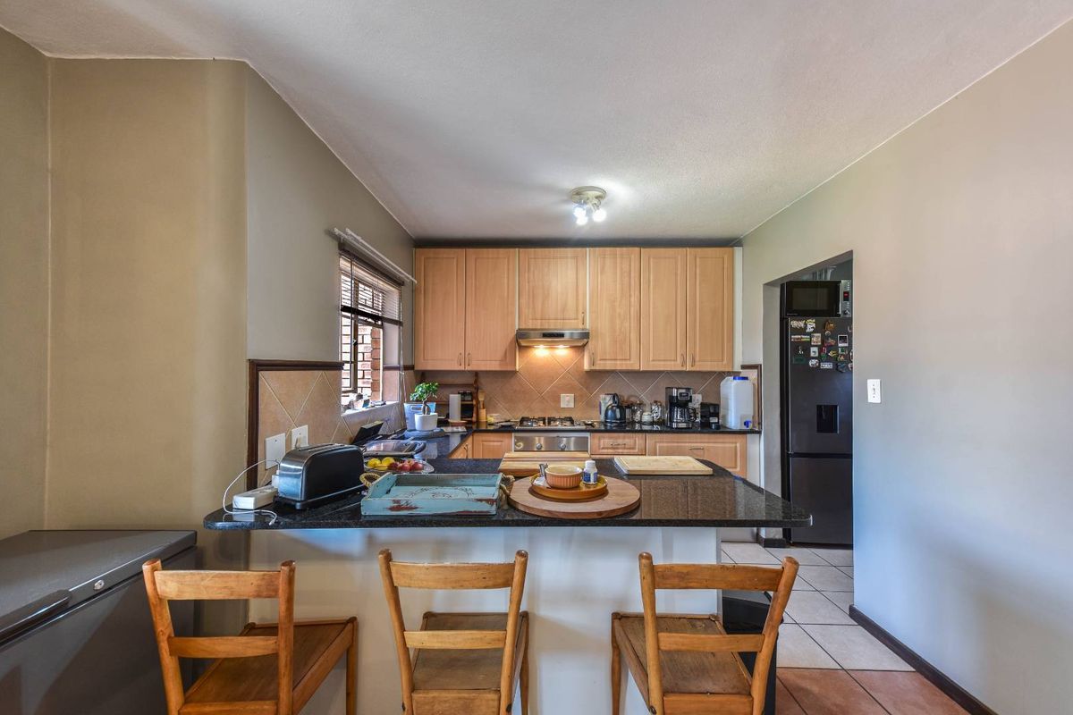 Functional kitchen featuring light wood cabinetry, granite countertops, a breakfast bar, and a tiled backsplash, providing a practical layout for daily cooking and dining.