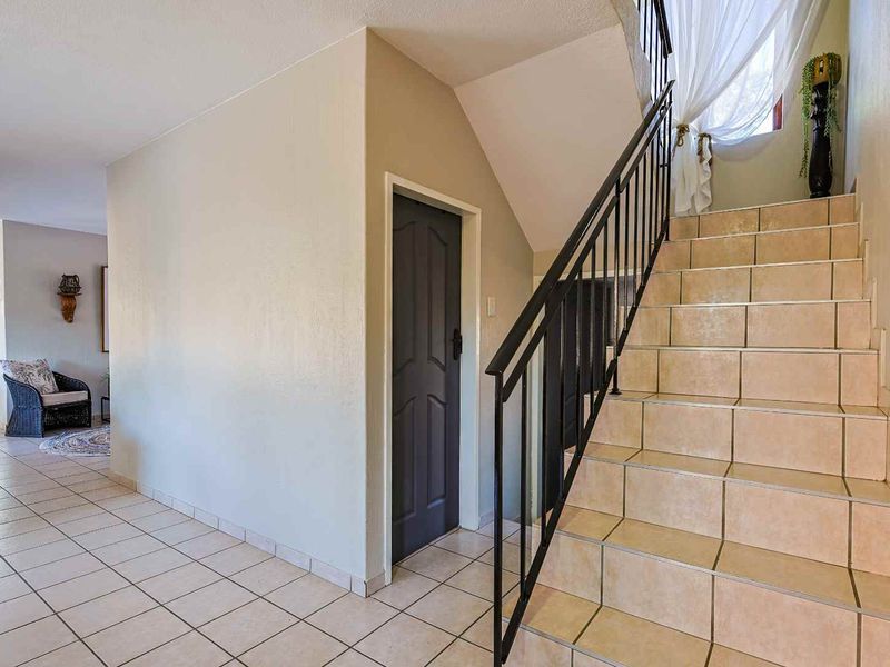 Entrance hall featuring a tiled staircase with a wrought iron balustrade and ceramic floor tiles leading to the main living area.