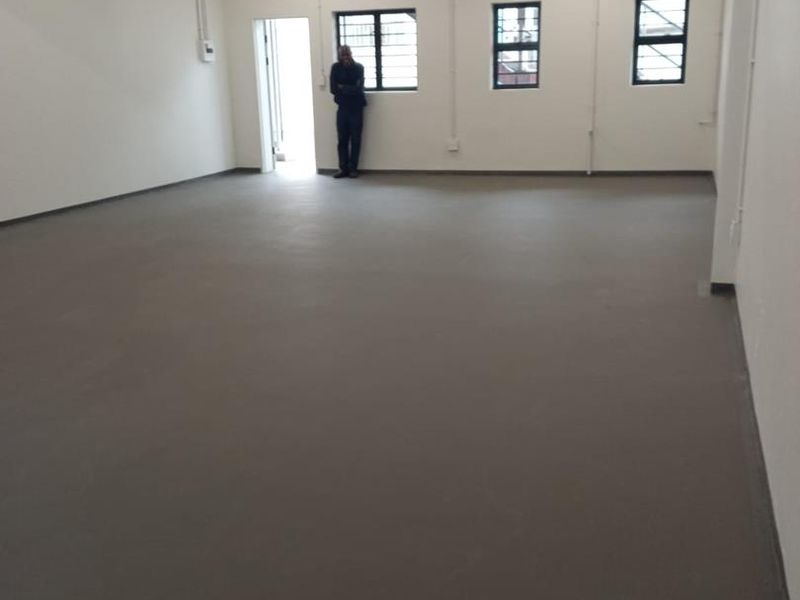 A spacious, open-plan industrial utility area featuring concrete flooring, exposed ceiling beams, and functional fluorescent lighting.