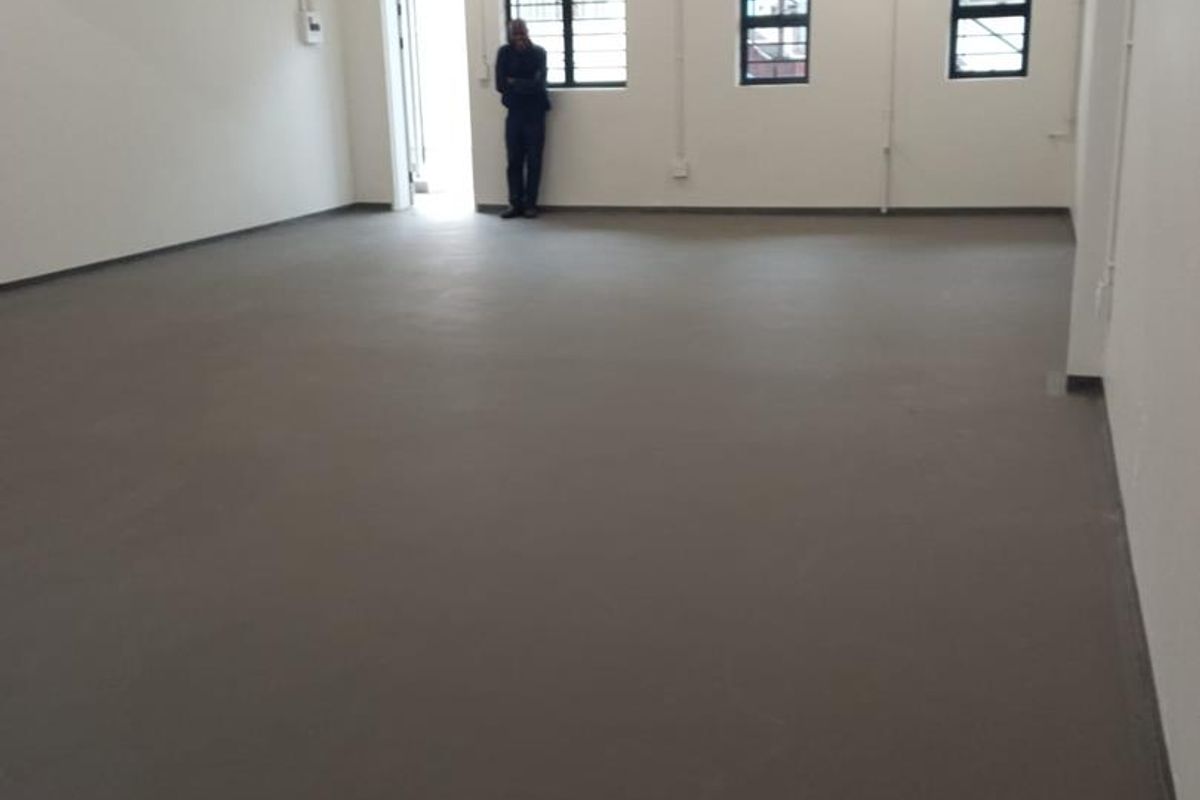 A spacious, open-plan industrial utility area featuring concrete flooring, exposed ceiling beams, and functional fluorescent lighting.