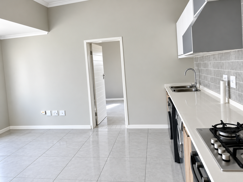 Modern kitchen featuring sleek cabinetry, stone countertops, gas hob, built-in oven, and neutral tiled flooring, offering a clean and functional culinary space.