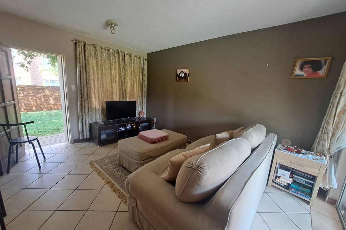 A living room featuring tiled flooring and direct access to an outdoor patio area through a glass door.