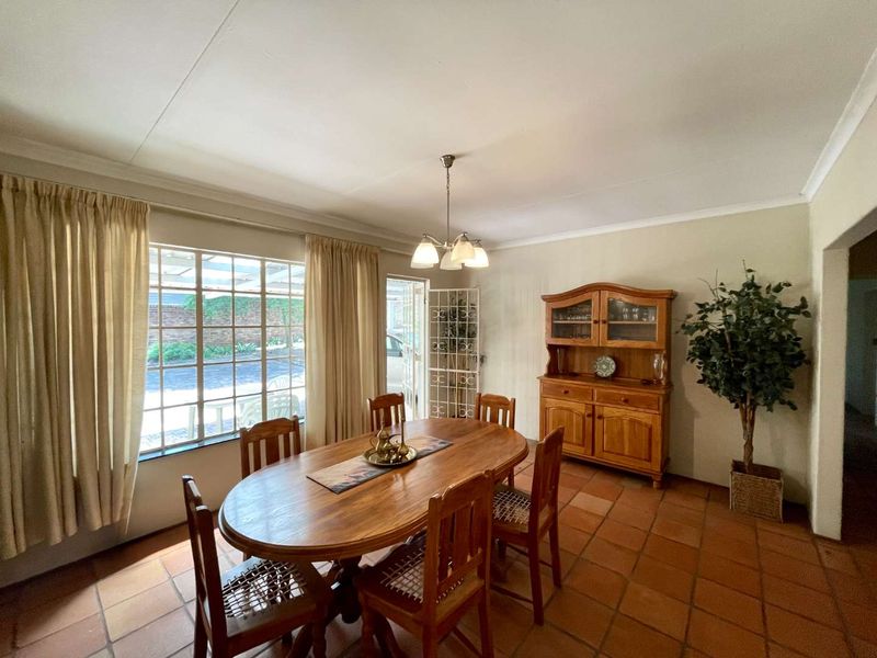 A dining room featuring terracotta floor tiles, coved ceilings, and large windows providing natural light and access to the exterior.