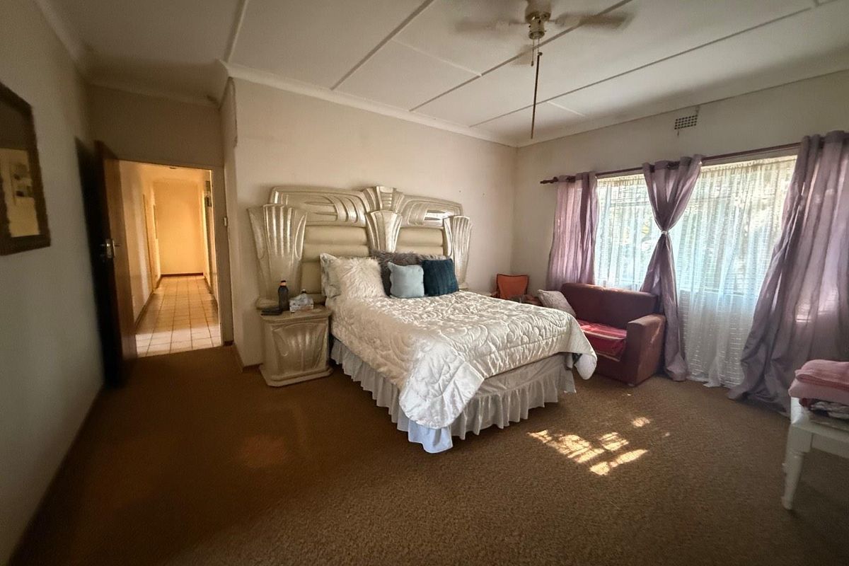 Spacious bedroom featuring carpeted flooring, a ceiling fan, and large windows allowing for natural light.