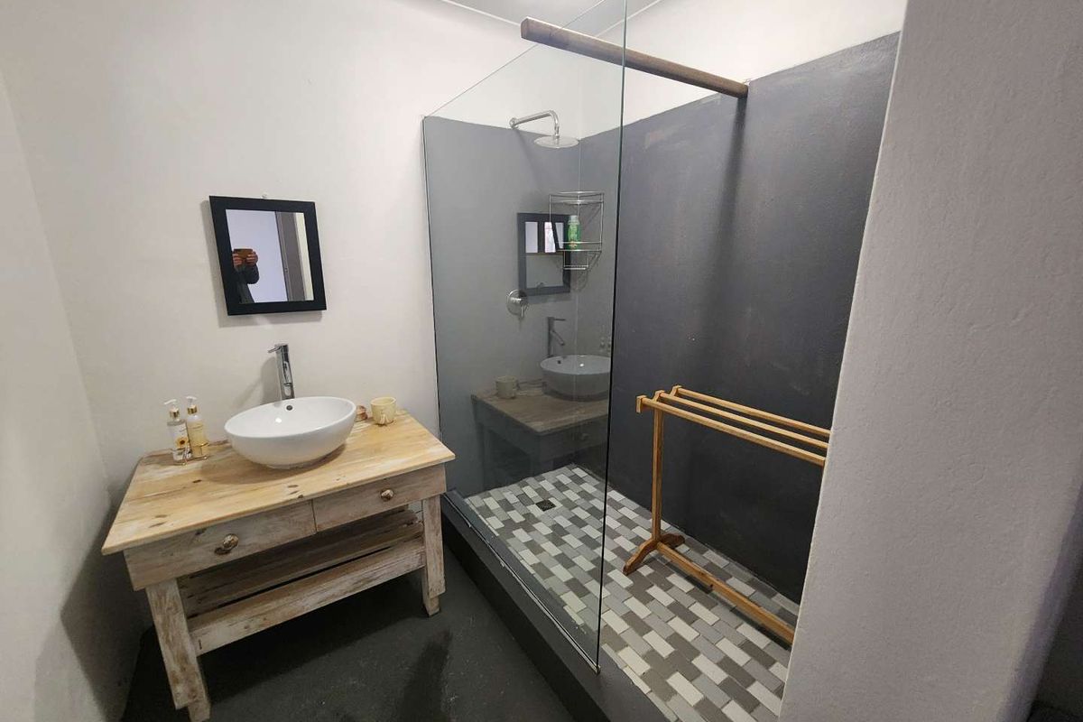 Modern bathroom featuring a walk-in shower with glass partition, tiled shower floor, and a rustic wooden vanity with a vessel sink.