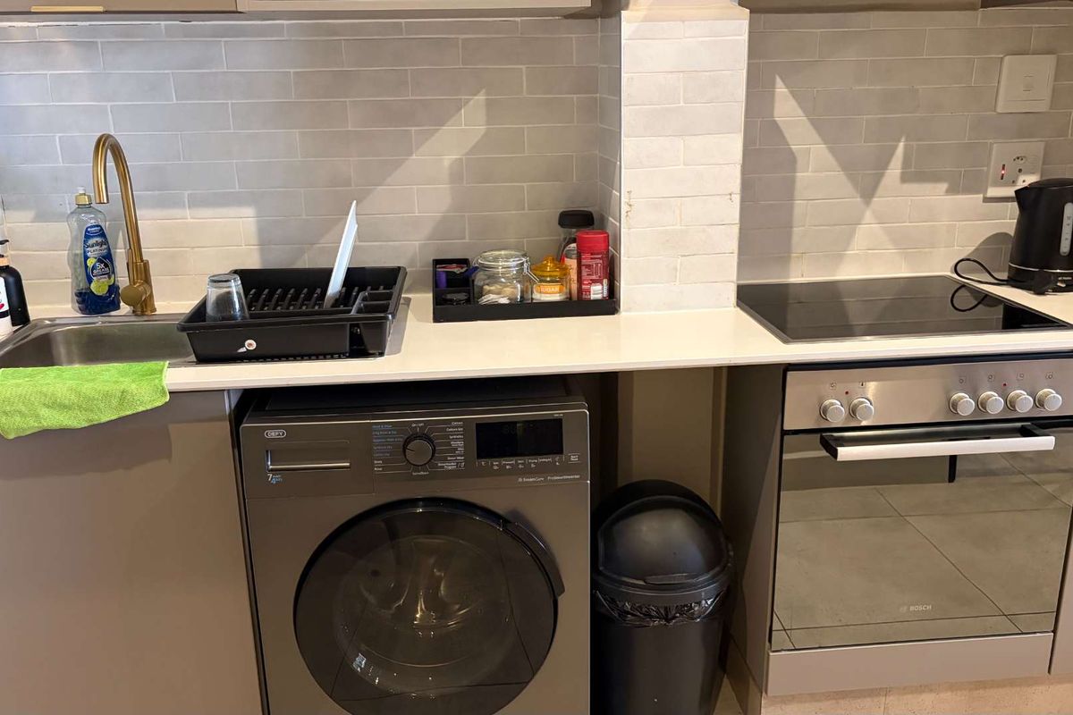 Modern kitchen featuring a subway tile backsplash, quartz countertops, brass faucet, built-in oven, and electric hob with integrated cabinetry.