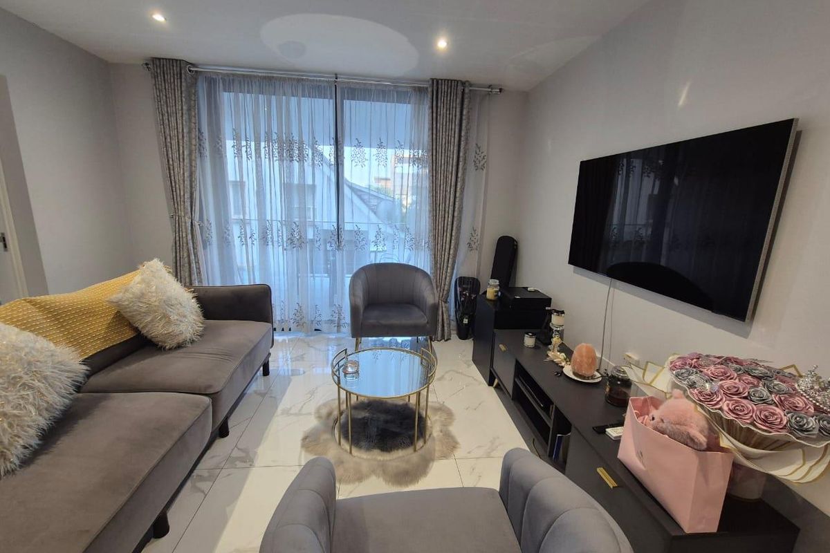 A modern living room featuring polished marble-look floor tiles, recessed downlighting, and a large sliding glass door providing natural light.