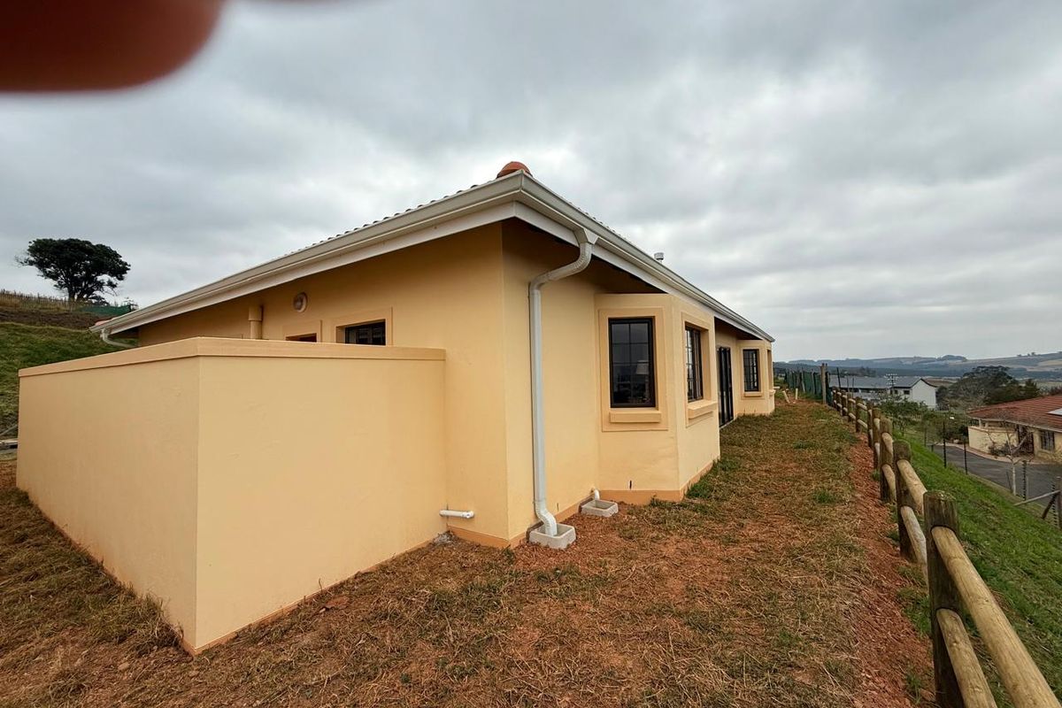 Exterior view of the townhouse rear elevation featuring painted masonry walls, guttering system, and timber post fencing along the perimeter.