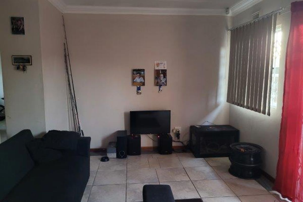 A living room area featuring tiled flooring, cornicing, and vertical blinds, providing a functional space for relaxation.
