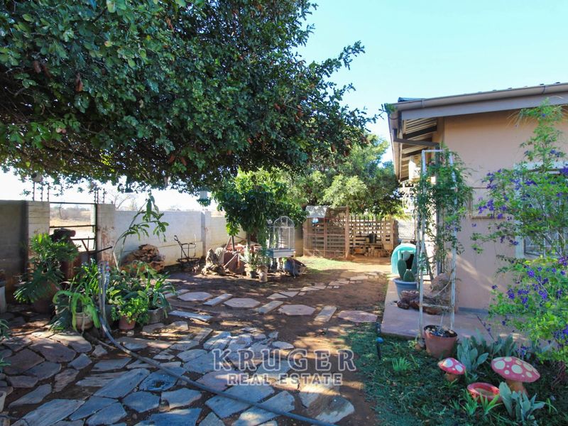 A rear garden area featuring stone paving, mature trees, and a boundary wall, providing a private outdoor space adjacent to the house.
