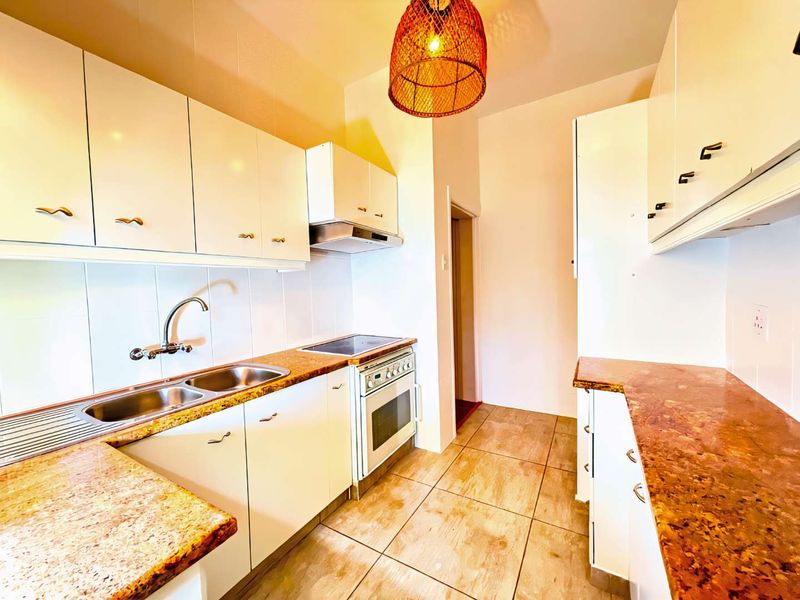 A functional kitchen featuring white cabinetry, stone-look countertops, a double basin sink, and a built-in electric stove with an extractor fan.