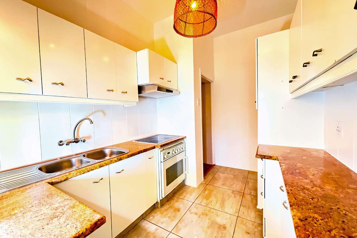 A functional kitchen featuring white cabinetry, stone-look countertops, a double basin sink, and a built-in electric stove with an extractor fan.