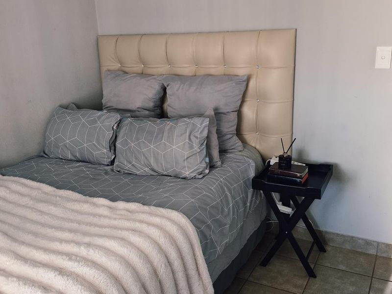 A bedroom featuring tiled flooring and neutral wall finishes, providing a functional and simple sleeping space.