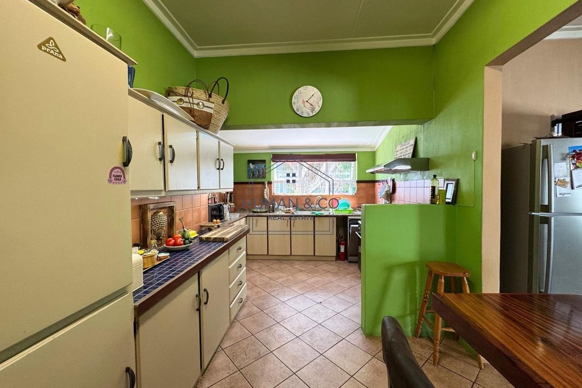 A functional kitchen featuring tiled countertops, built-in cabinetry, and a tiled floor, offering a practical layout with potential for modern updates.