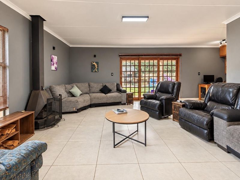 Spacious living room featuring large format floor tiles, a modern freestanding fireplace, and sliding glass doors providing access to the outdoor area.