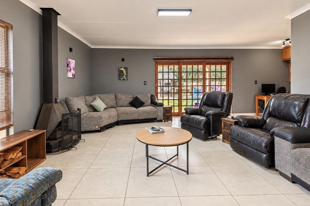 Spacious living room featuring large format floor tiles, a modern freestanding fireplace, and sliding glass doors providing access to the outdoor area.