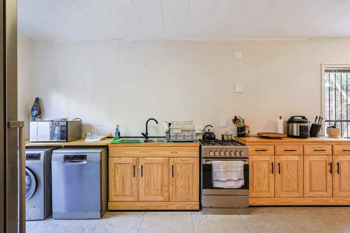 Functional kitchen featuring wooden cabinetry, stainless steel stove, integrated dishwasher space, and tiled flooring.