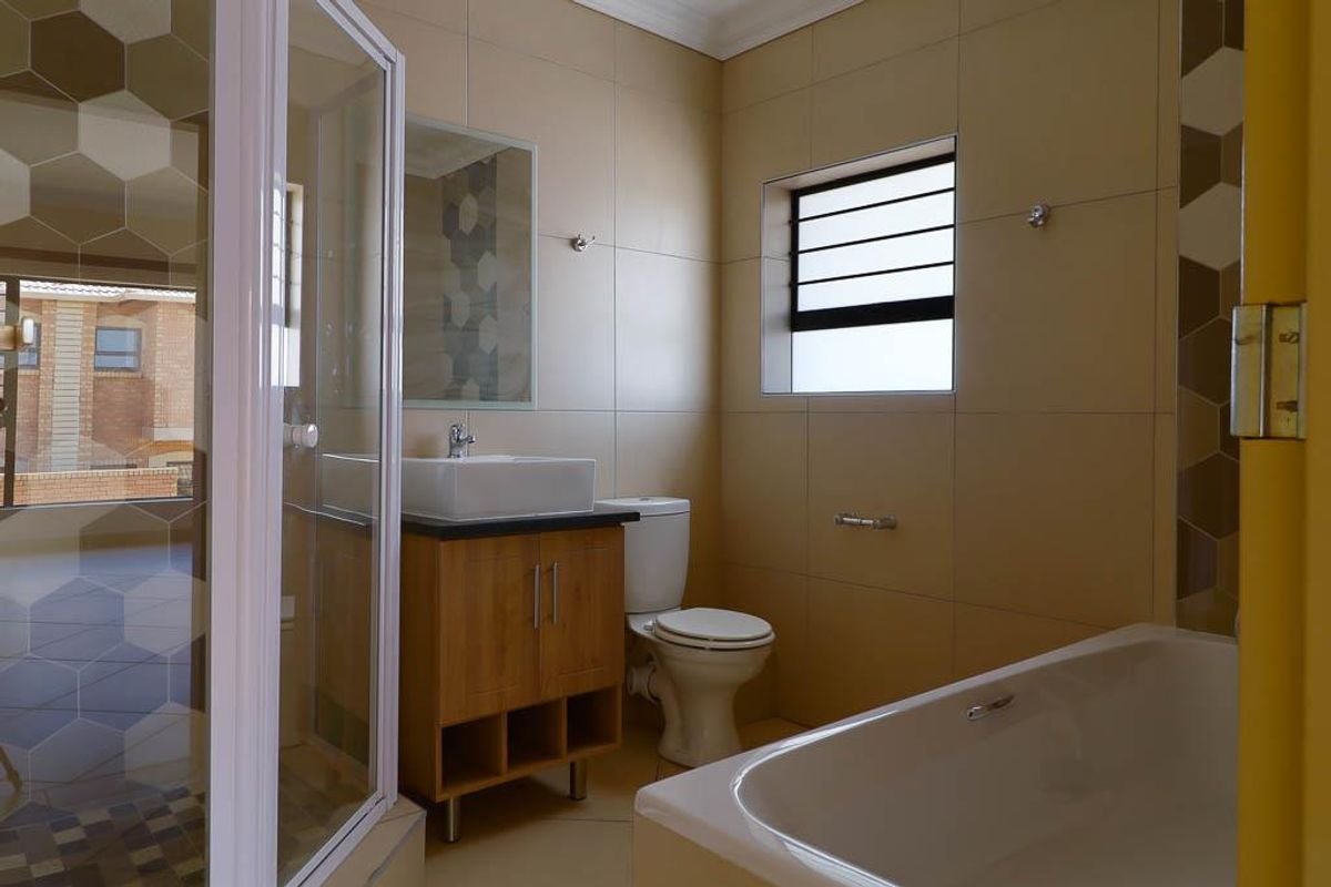 A clean, modern bathroom featuring a separate shower enclosure, bathtub, vanity with vessel sink, and neutral wall tiling.