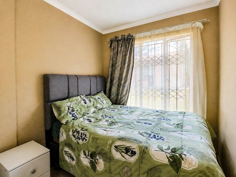 A cozy bedroom featuring neutral wall tones, a window with a fitted security gate, and classic coving detail.